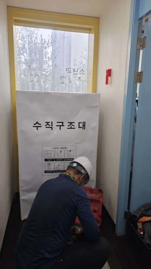 수직구조대 현장설치 현장 사진 — 수납함 하단부를 작업 중인 담당자