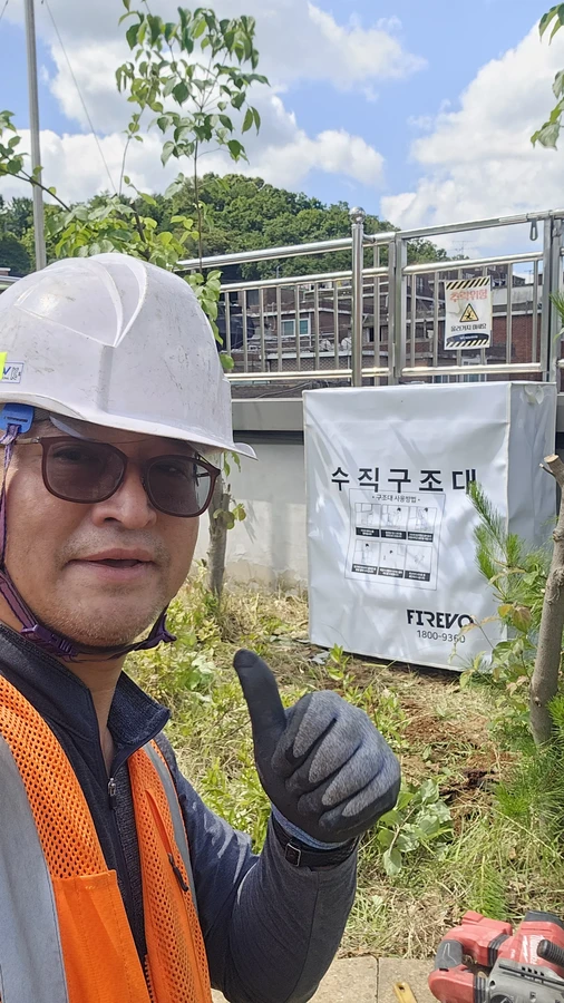 수직구조대 시공사례 현장 사진 — 옥상 난간 앞 수직구조대 설치 현장의 담당자